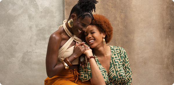 Two women embracing each other against a textured wall.